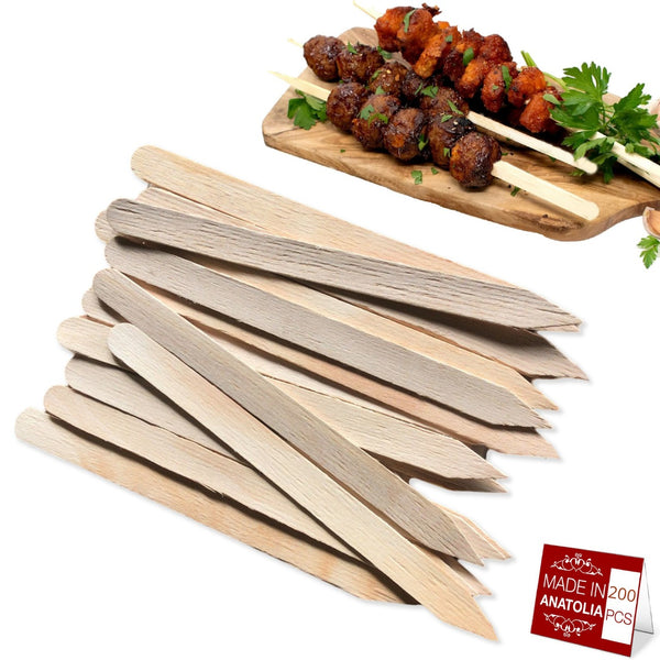 A pile of Hakan 200-Pack Wooden Flat Skewers for Grilling (9.8x0.39) is in the foreground; in the background, grilled meat kabobs with parsley are shown beside a red MADE IN ANATOLIA 200 PCS label.